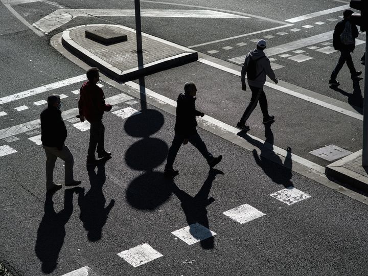 A group of people walking across a street.