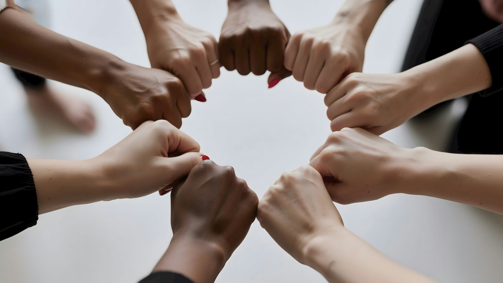 People of diverse skin tones fist bumping in a circle.